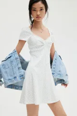Vestido corto blanco con estampado floral celeste, de punto acanalado con escote corazón ribeteado en encaje y cordón para ajustar en el centro del busto. Modelo de manga corta con cuerpo entallado, copas preformadas y pollera con vuelo.