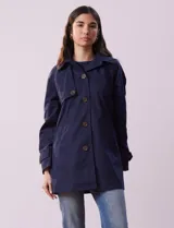 Gabardina impermeable color beige, marca Weatherproof, con abertura central con botones, bolsillos delanteros y capucha desmontable.