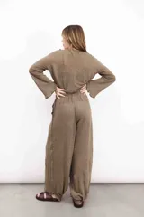 Pantalón de lino azul con tiro medio, elástico y lazo en la cintura, y puño con botón de nácar en el tobillo.