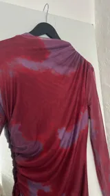 Vestido midi de microtul doble, color borgoña con estampado difuminado en tonos lila. Tiene cuello alto y mangas largas de una sola capa de microtul.