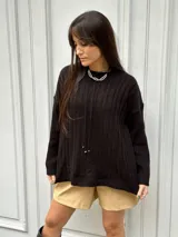 Sweater tejido color salmón, con cuello redondo y diseño de ochos en el frente y rayas en las mangas.