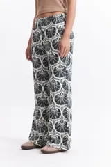 Pantalón wide leg estampado con diseño de conchas marinas color marrón sobre fondo blanco.
