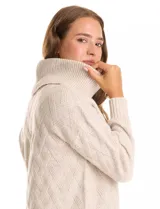 Buzo de punto grueso color beige, con cuello volcado y textura en relieve. Tiene mangas largas de corte hombro caído y puños anchos.