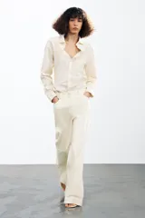 Camisa color crema de algodón y lyocell, con cuello solapa, manga larga con puños y bolsillo de parche en el pecho.