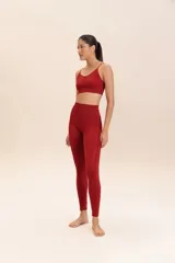 Conjunto deportivo color borgoña, compuesto por un top deportivo de tirantes finos y calzas de compresión media, sin costuras, de textura suave y alta transpirabilidad.