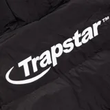 Campera puffer negra con capucha y logo Trapstar en la espalda.