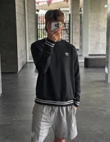 Buzo celeste de corte clásico con logo Umbro bordado en el pecho. Presenta cortes y cambio de color en las mangas, y ribete con rayas grises en cuello, puños y cintura.