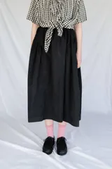 Falda midi negra con cintura elastizada y frunces en los lados.