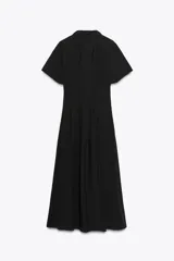 Vestido midi de algodón color negro, con cuello solapa, manga corta y falda evasé. Cierre frontal con botones y lateral con cremallera oculta.