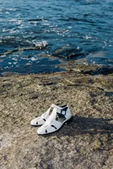 Sandalia de cuero color marrón, con diseño de tiras entrecruzadas y hebilla lateral.