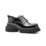 Zapato acordonado de cuero color marrón con costuras blancas y suela track con plataforma.