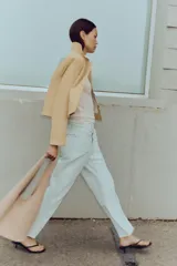 Jeans tobilleros de tiro alto color blanco, corte recto y bajo sin costura. Cierre frontal cruzado con cremallera y botones.