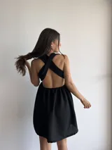 Vestido corto negro con escote halter y espalda descubierta. Presenta un corte a la cintura con falda acampanada.