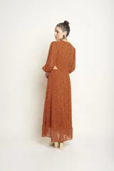 Vestido largo color naranja con estampado de manchas negras, escote en V, mangas largas abullonadas y corte evasé.