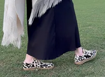 Zapatillas bajas con estampado animal print de vaca en blanco y negro, con cordones marrones y suela color caramelo.