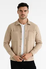 Sobrecamisa beige de corte recto, con cuello camisero, cierre frontal con botones a tono, mangas largas con puños abotonados, dos bolsillos de parche en el pecho y ruedo recto.