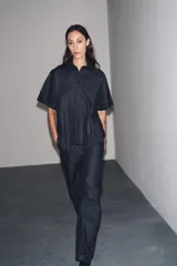 Pantalón de denim azul oscuro, de tiro medio y corte ancho, con cintura elástica en la parte trasera y cierre frontal con cremallera y botón.