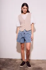 Chaleco de punto color beige con cuello en V y cierre frontal con botones.