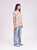 Remera estampada con motivos florales en tonos naranja, beige, gris y rosa.