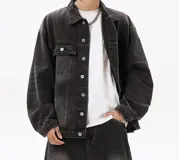 Campera de jean negra con efecto gastado y roturas. Diseño de corte amplio (boxy) con cuello, cierre frontal de botones, bolsillos con solapa en el pecho y bolsillos laterales.