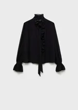 Blusa negra de tejido fluido con cuello alto, cierre frontal oculto con botones, mangas largas con puños elásticos y volantes.