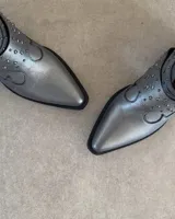 Botines negros de cuero con textura de piel de serpiente, punta fina, cierre lateral y apliques de tachas plateadas.