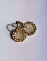 Par de aros colgantes con dije circular de resina con glitter multicolor y borde de strass. El arito es de acero quirúrgico dorado.