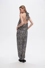 Pantalón slouchy de viscosa con estampado floral en tonos beige y negro, bolsillos laterales, cintura alta y detalle de punto smock en los tobillos.