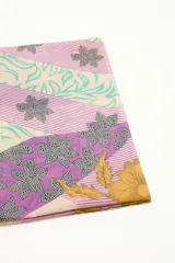 Pareo rectangular de algodón con estampado de margaritas en tonos beige, amarillo, celeste y lila.