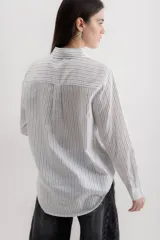 Camisa blanca a rayas verticales negras, de corte clásico, con cuello camisero y mangas largas con puños abotonados.