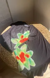 Conjunto de top y falda larga de color negro con estampado de flores rojas y verdes. El top es de mangas cortas y la falda tiene elástico en la cintura.
