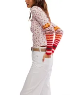 Top de manga larga ajustado, color negro con estampado floral pequeño en tonos beige y amarillo. Presenta cuello alto tipo mock con borde festoneado y puños alargados de punto con diseño multicolor a rayas y patrones geométricos en tonos azul, verde, marrón y negro.