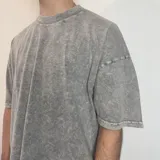 Remera gris con efecto acid wash, corte boxy fit y logo ovalado en la espalda.