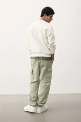 Pantalón cargo color verde claro, de corte relajado, con bolsillos laterales con solapa y botón a presión. Confeccionado en popelina de algodón con elástico en la parte posterior de la pretina y cierre con botón a presión.