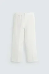Pantalón blanco de lino con corte relajado (relaxed fit), cintura elástica, bolsillos frontales y un bolsillo trasero de vivo.