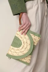 Sobre de rafia combinado en tonos verde y beige con lurex dorado. Incluye correa de mano de cuero marrón y gancho metálico.