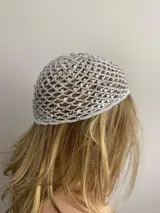 Gorro tipo mesh cap tejido a crochet en hilo color crema, con lentejuelas iridiscentes.