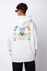 Buzo canguro gris claro de corte oversize, con capucha y cordones negros con letras blancas. Presenta un bolsillo tipo canguro y un estampado pequeño en el pecho y otro en la manga.