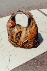 Bolso de mano con cuerpo cubierto de abalorios y bordados multicolores. Tiene asa de mano doble y correa metálica extraíble para usar como bandolera. El cierre es imantado.