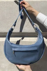 Cartera bandolera color gris topo con apliques de tachas metálicas plateadas.