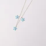 Tobillera dorada con cadena de eslabones y tres dijes de flores de resina celeste con un strass en el centro.