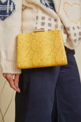 Clutch amarillo con textura de piel de serpiente, cierre metálico dorado y cadena fina dorada.