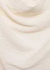 Blusa blanca de tejido fluido con textura, manga corta, cuello alto envolvente y cierre de cremallera en la parte posterior.