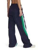 Pantalón deportivo Under Armour para mujer, confeccionado en tejido ligero con textura arrugada y paneles laterales a presión. Diseño de corte holgado con cintura elástica y logo de la marca bordado en verde.