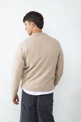 Suéter de punto suave color beige, con cuello polo y detalle de tres botones en la parte frontal. De manga larga y tejido abrigado.