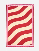 Pareo rectangular de algodón con diseño de ondas rojas y beige, bordeado con una guarda rosa y flecos.