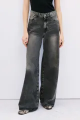 Jean oxford tiro alto de denim negro con lavado stone y bigotes. Pierna ancha desde la cadera.