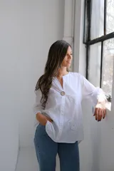 Blusa blanca de mangas largas con cuello mao y cierre frontal con botón de madera.
