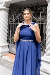 Vestido largo de fiesta color azul francia, con apliques de flores en la cintura y capa incluida.