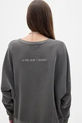 Buzo gris de algodón lavado, corte oversized, manga larga, hombros caídos y cuello redondo. Bordado pequeño en el frente y bordado grande en la espalda, ambos a tono.